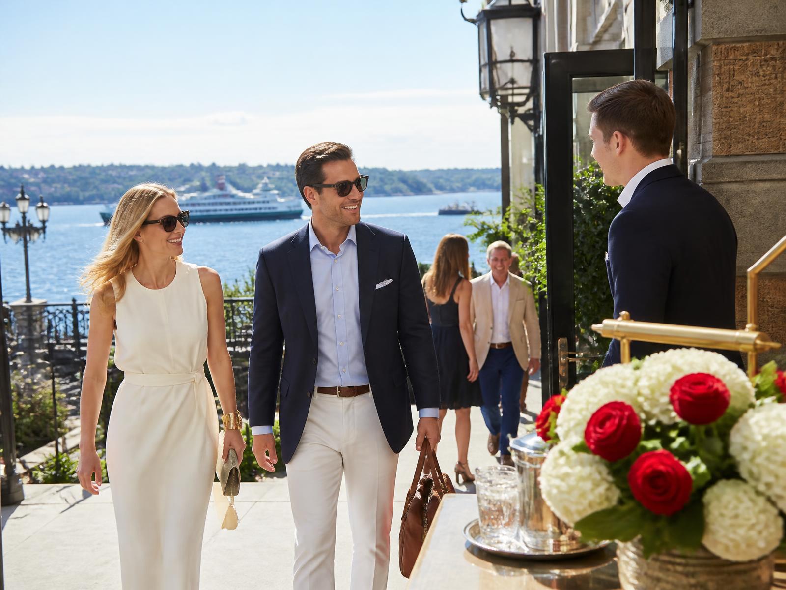Guests arriving at a bright Seattle waterfront hotel terrace on a clear morning